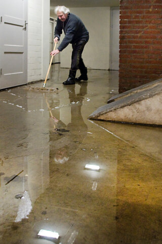 Man veegt water met een mop in een ondergelopen kelder.